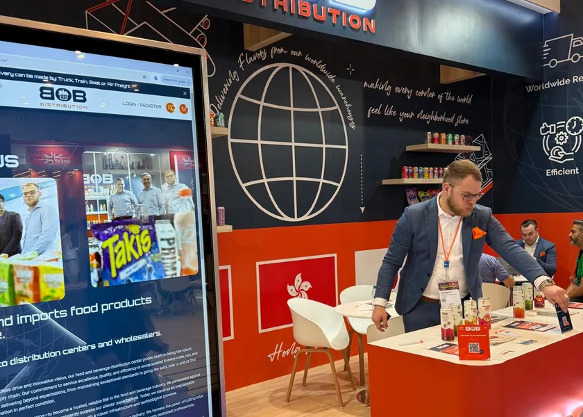 A large screen showing the BOB Distribution website at the stand, with a staff member at the counter in the background.