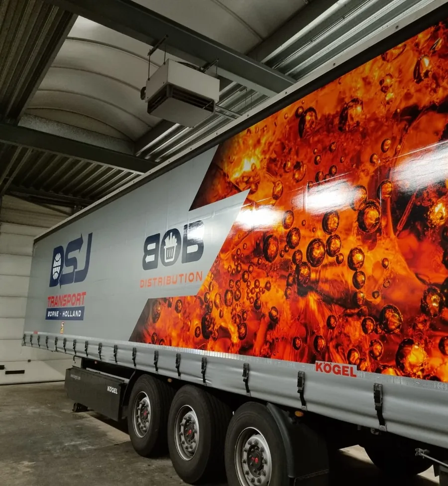 A trailer with the logos of BOB Distribution and DSJ Transport from Borne, with a large photo of fizzing soft drink on its side.