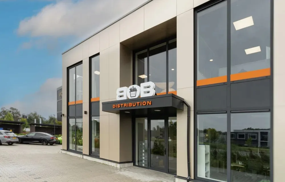 The BOB Distribution building: a modern façade with large windows, an orange band and the BOB logo above the entrance.